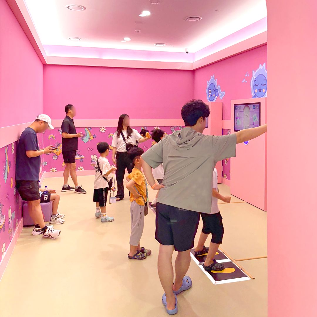 분홍색 체험 룸에서 게임을 즐기는 방문객들